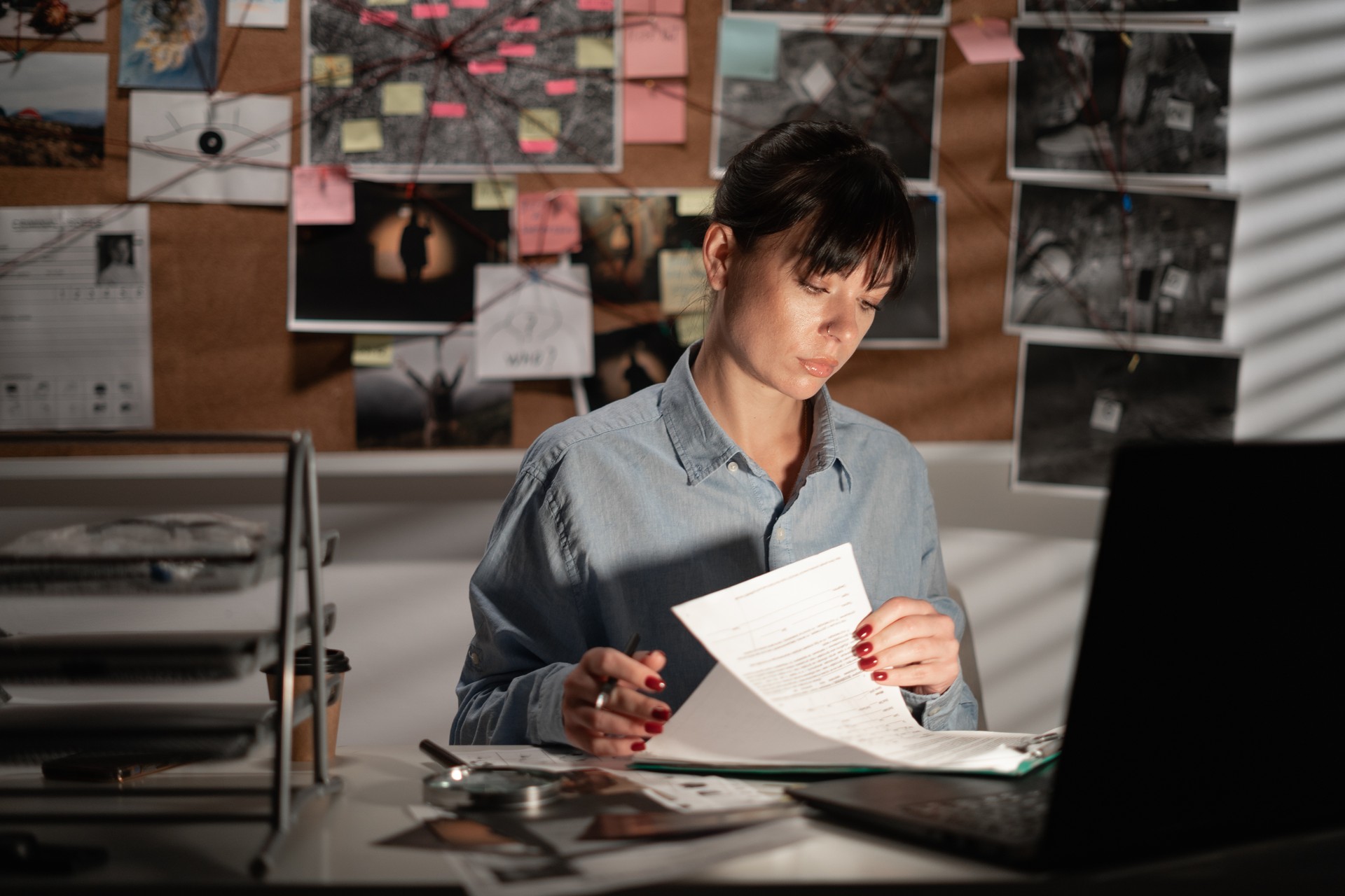 Female Detective processing evidence in office using laptop computer at night